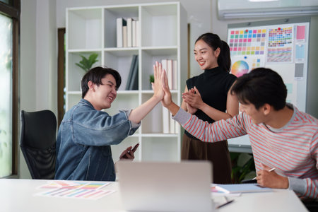Collaboration and Creativity. Three graphic designers discussing design concepts and brainstorming ideas in a modern workspace.の写真素材