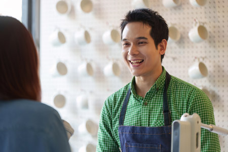 Customer Service and Engagement. A friendly barista smiles warmly, providing excellent service in a modern cafe setting.の写真素材