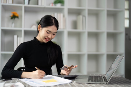Smiling young woman enjoying financial planning with credit card at home