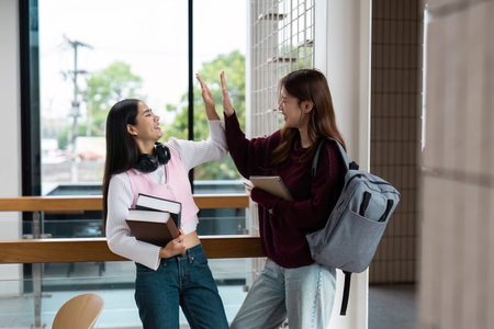 Celebration and Achievement. Friends high-fiving after a successful study session in a bright educational environment.の写真素材