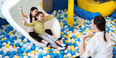 Playful Children Enjoying Slide in Colorful Ball Pitの写真素材