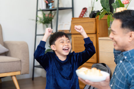Excited Boy Enjoying Treats from Father. A young boy expresses joy while receiving snacks.の写真素材