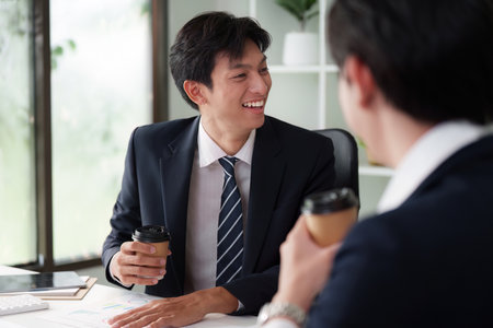 Team Building and Innovation. Excited professionals discussing projects with coffee in hand, promoting a thriving work culture.の写真素材