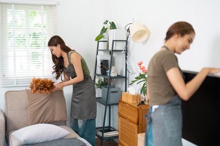 Cleaning and Home Organization. Two women tidying up their living space together, creating a fresh and inviting atmosphere.の写真素材
