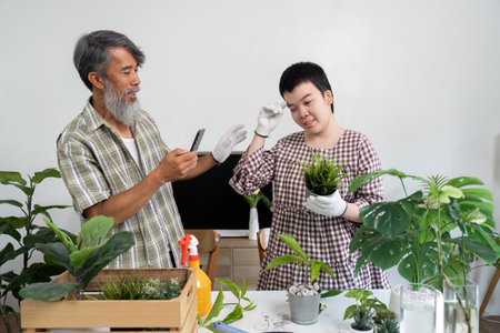 Plant Care and Learning. A young person receives guidance from an experienced gardener while potting plants.の写真素材