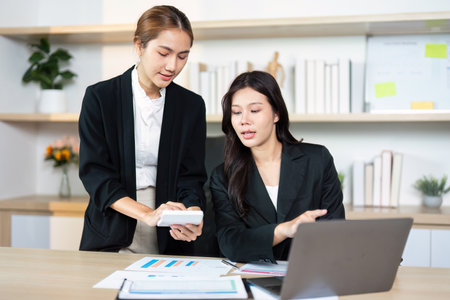 Teamwork in Action. Two women collaborating on business strategy with a smartphone.の写真素材