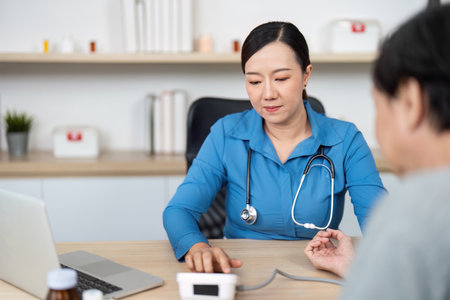 Doctor using blood pressure monitor during patient consultation in clinic