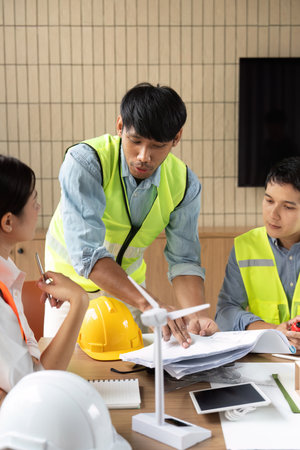 Sustainability and Engineering Discussion. An engineer explaining project details to colleagues in a collaborative setting.の写真素材