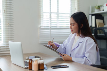 Female doctor reviewing patient notes and medical records at deskの写真素材