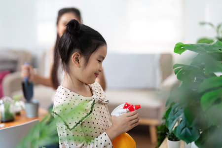 Child Learning Plant Care. Young girl watering indoor plants.の写真素材
