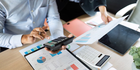 Comprehensive Financial Review. Professional analyzing data with a calculator and charts in the...