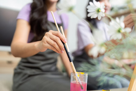 Couple Painting Together. Two young women enjoying a creative moment while painting in a cozy indoor setting.の写真素材