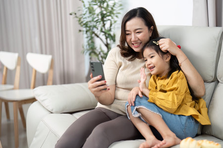 Mother and Daughter Smiling Together. Capturing joyful video moments on a smartphone.の写真素材