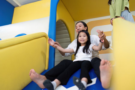 Joyful Sliding. A mother and daughter having fun on a colorful slide.