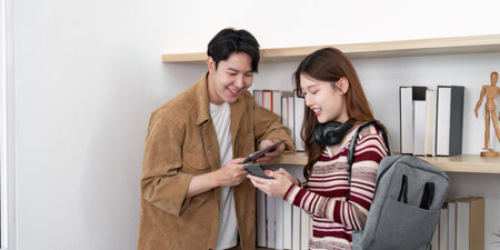 Tech Sharing Moment. Young couple exchanging ideas with devices in modern workspace.の写真素材
