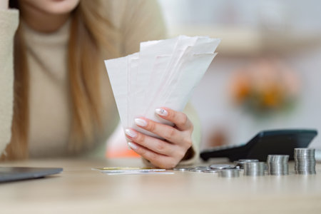 Financial Stress and Budgeting. Woman reviewing bills and receipts at home with concern.の写真素材