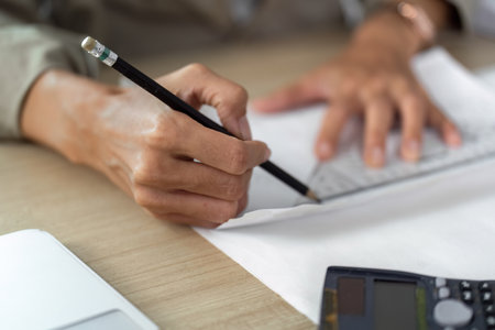 Architect drafting plans with pencil on workspaceの写真素材