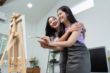 LGBTQIA Couple Creating Art Together. Two women joyfully painting and sharing creative moments in a cozy studio.の写真素材