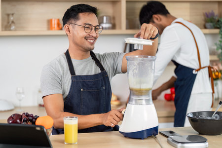 LGBT Couple Preparing Smoothies Together in Kitchenの写真素材