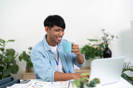 Remote Work and Refreshment. A man enjoying coffee while working from home, emphasizing relaxation and productivity.の写真素材