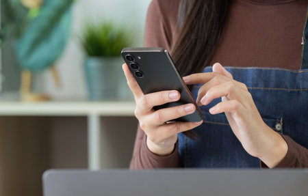Digital Communication. Woman using smartphone in a plant shop.の写真素材