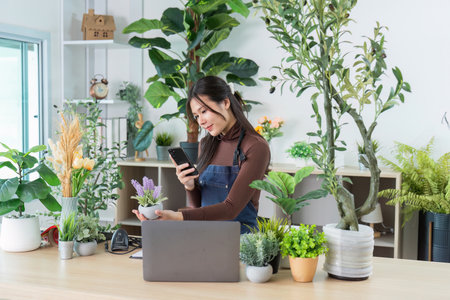 Florist engaging with smartphone while showcasing plantsの写真素材