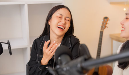 Cheerful women laughing during a podcast sessionの写真素材