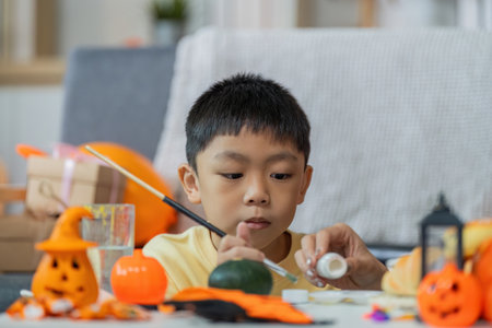 Halloween Crafting Fun. A young boy painting Halloween decorations at home.