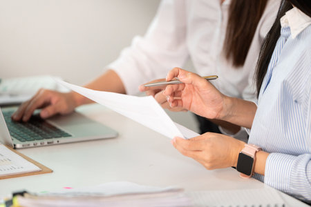 Professional Collaboration. Woman reviewing documents while working with a colleague.