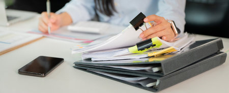 Organized Workspace. Woman managing documents and files in a busy office.