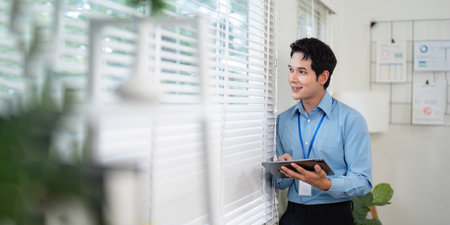 Smiling Young Professional Using Tablet by Window