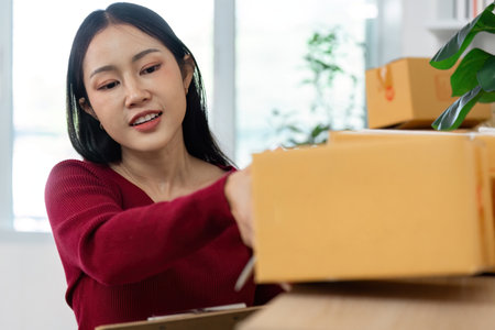 E-commerce. Woman organizing packages and managing orders at home.の写真素材