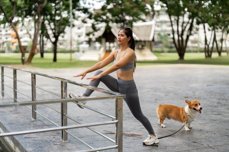 Stretching Exercise. Woman and Corgi in Parkの写真素材