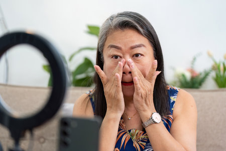 Skincare Application. Mature woman applying serum in front of a camera.の写真素材