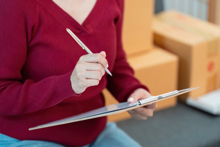 Efficient Delivery Management: Woman Taking Notes with Penの写真素材