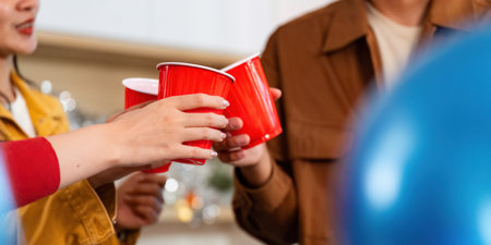 Cheers at a party, friends toasting with red cups in a lively atmosphereの写真素材
