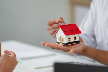 Real Estate Consultation. Agent presenting a miniature house model to a client.の写真素材