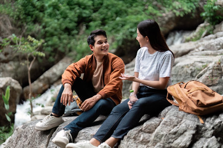 Couple Relaxing Outdoors. Young man and woman sitting on rocks, enjoying conversation during a hike.