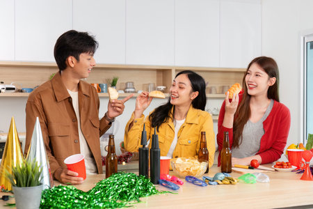 Friends enjoying snacks and drinks at a lively partyの写真素材
