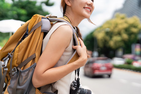 Travel. Young woman with backpack smiling on busy city street.の写真素材