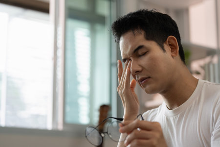 Mental Health. Young man experiencing stress and headache relief at home.の写真素材