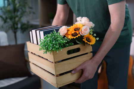 Close-up of hands carrying a crate with flowers and booksの写真素材
