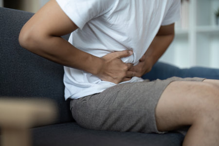 Physical Health. Young man suffering from back pain while sitting on couch.の写真素材