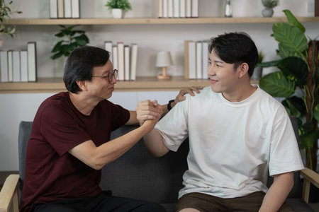 Friendship Bond. Two friends sharing a heartfelt handshake in a cozy setting.の写真素材