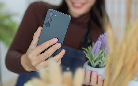 Sustainability. Woman taking selfie with smartphone and potted lavender plant indoors.の写真素材