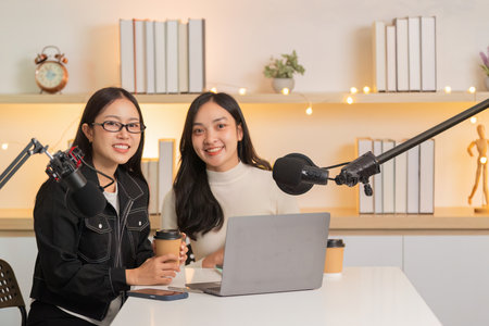 Podcast Studio. Two women smiling and preparing for a recording session with laptops.の写真素材
