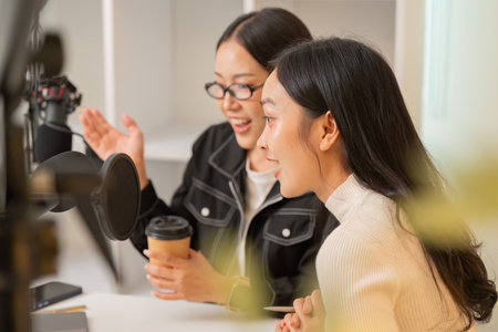 Podcast Recording. Two women engaging in lively discussion with microphones and coffee.の写真素材