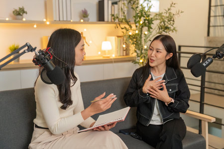 Podcast Recording Session. Two women animatedly discussing topics on a couch.の写真素材