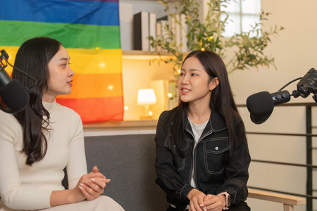 Empowering Dialogue. Women discussing ideas with pride flag in the background.の写真素材