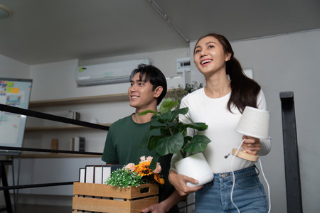 Home Transition. Couple carrying plants and unpacking boxes in their new space.